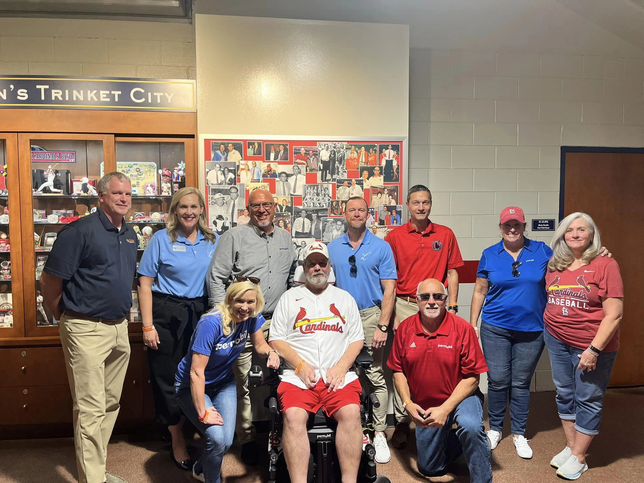 Group photo. At center former Permobil employee and person living  with ALS Alan Brown and Ashley Davis of the Permobil Foundation. Backstage at the Cardinals game