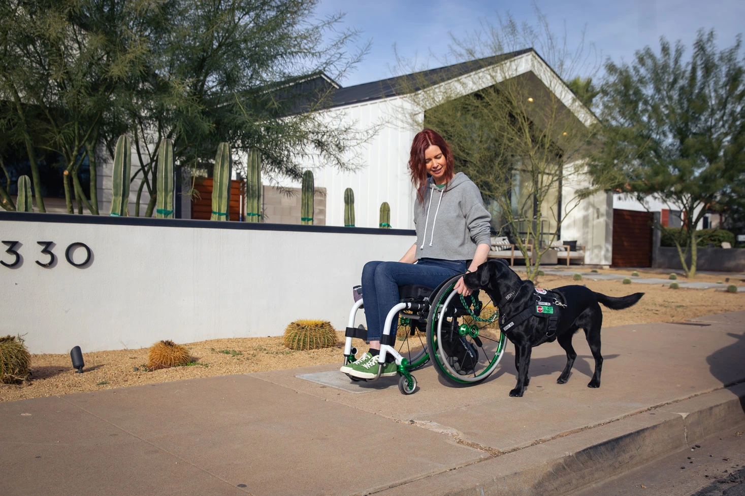 A lady wheeling next to a black Labrador dog 
